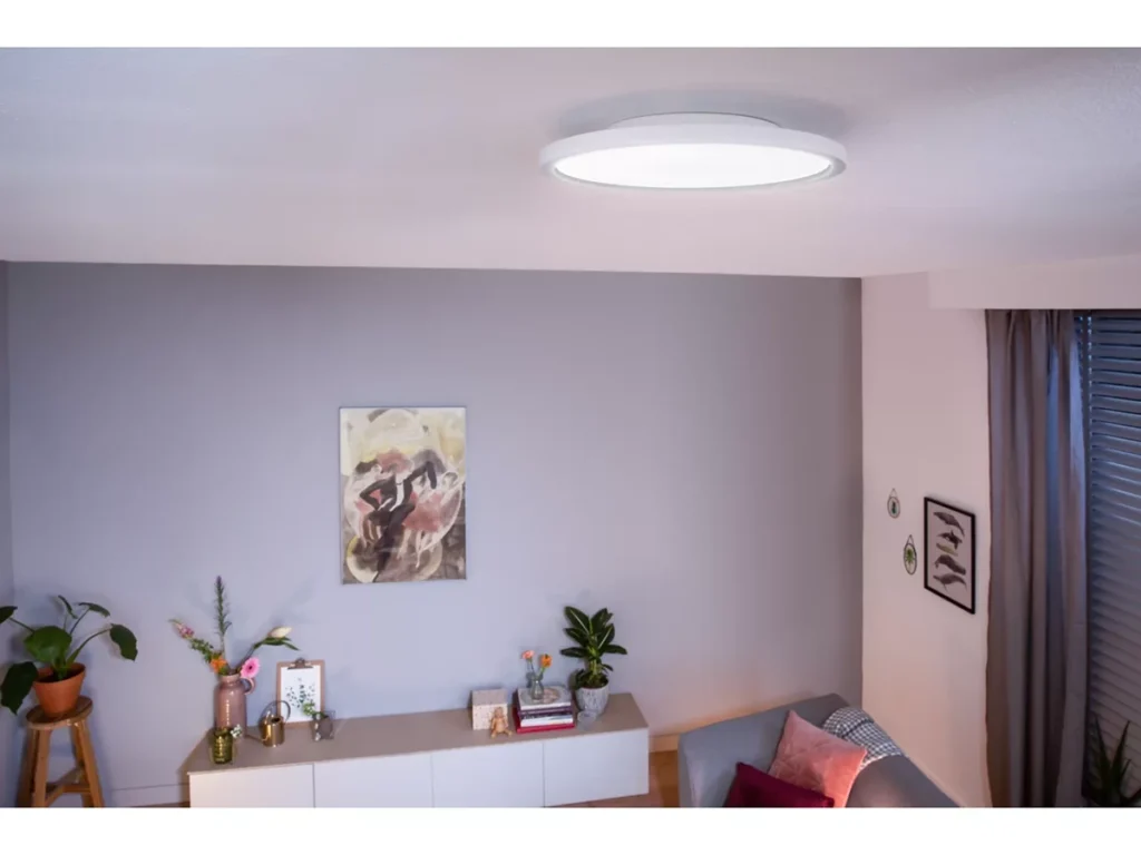 Plafón redondo Philips Hue Aurelle instalado en el techo de un salón moderno, iluminando la estancia