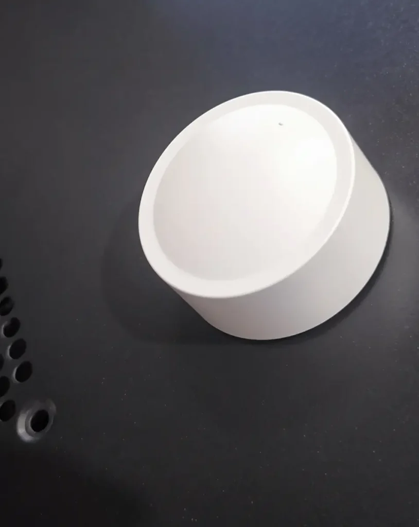 La perilla inteligente Tuya ZG-101Z/D adherida magnéticamente al lateral metálico de una torre de PC, demostrando la versatilidad y potencia de su base imantada.
