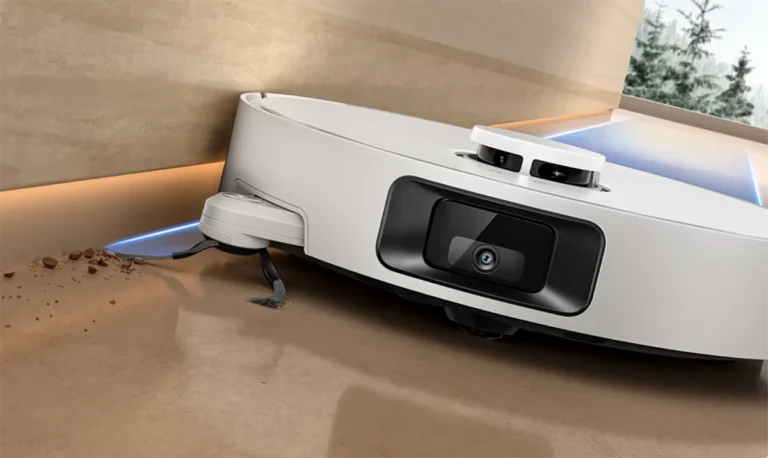 El robot aspirador Dreame D20 Pro Plus utilizando su cepillo lateral extensible para limpiar la suciedad de un borde. La imagen demuestra su capacidad para alcanzar esquinas y rincones difíciles.