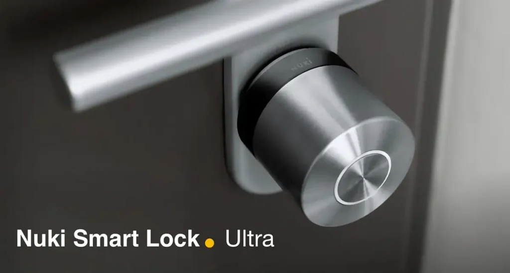 Primer plano de la cerradura inteligente Nuki Smart Lock Ultra. El dispositivo, con acabado en acero inoxidable, está instalado en una puerta oscura con la manivela desenfocada al fondo. nuki home assistant
