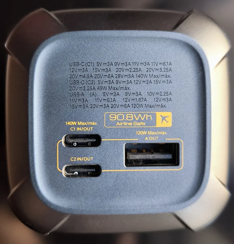 Primer plano detallado del panel de puertos de la Xiaomi 212W Power Bank. La imagen muestra los dos puertos USB-C (C1 y C2) y el puerto USB-A, con sus potencias máximas de 140W y 120W indicadas. En el centro, una etiqueta amarilla resalta la capacidad de 90.8Wh y el texto 'Airline Safe' con un icono de avión, confirmando que es apta para vuelos