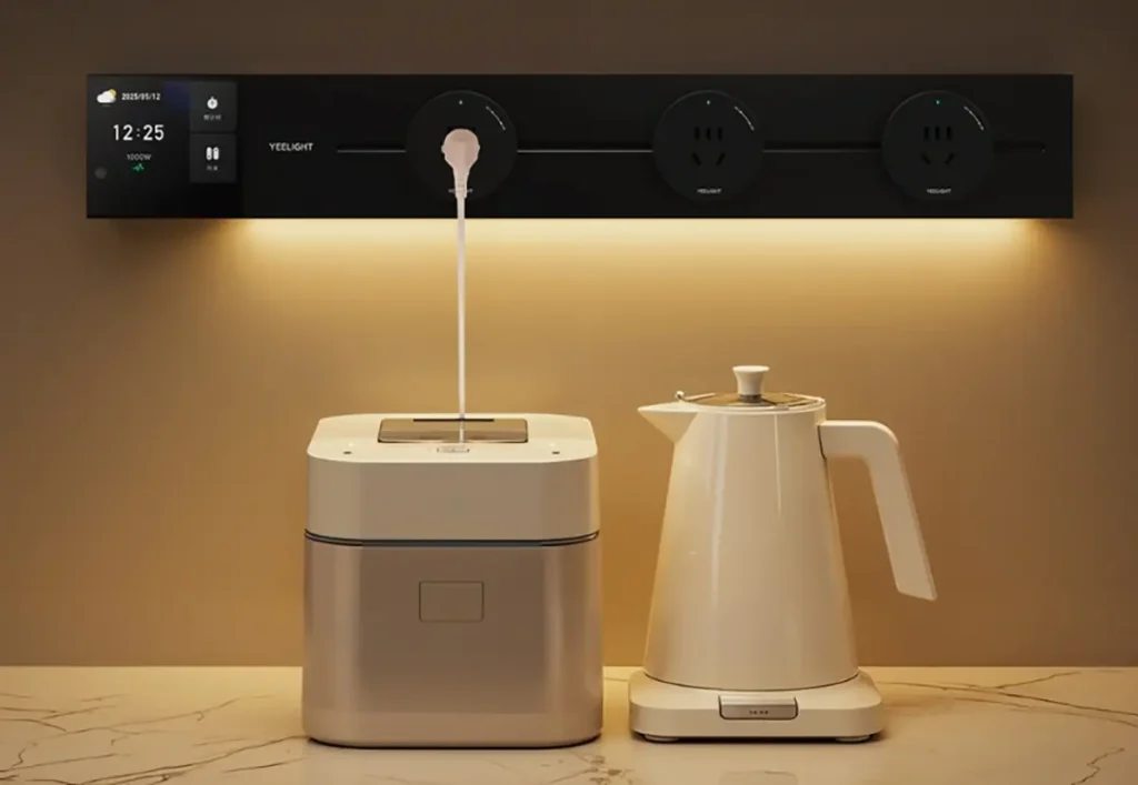 La regleta inteligente Yeelight instalada en la pared de una cocina. Su pantalla táctil muestra el consumo eléctrico y su luz ambiental ilumina un hervidor de agua y otro electrodoméstico sobre la encimera