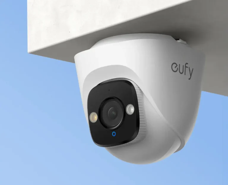 Cámara de seguridad para exteriores Eufy PoE Turret E41 de color blanco, instalada bajo el alero de una casa con un cielo azul de fondo.