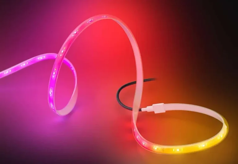 Primer plano de la nueva tira LED Philips Hue Outdoor Gradient Lightstrip mostrando su efecto de color gradiente, con una transición suave de tonos magenta, rojo y amarillo cálido sobre un fondo oscuro.