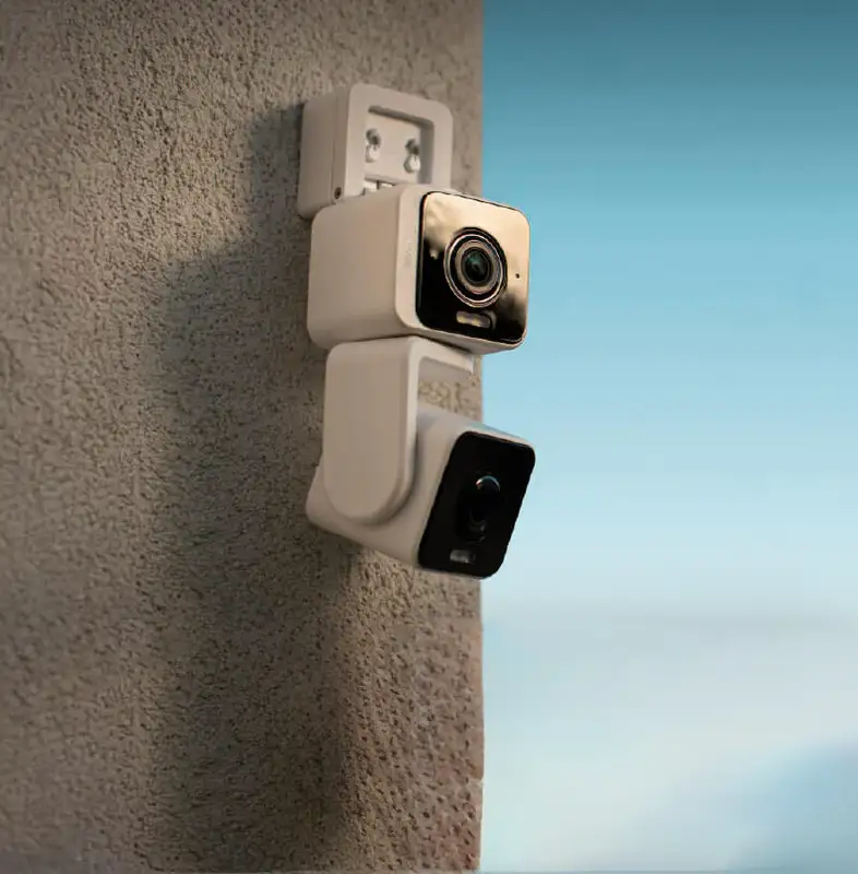 Cámara de seguridad Wyze Duo Cam Pan con doble lente instalada en una pared exterior de estuco, mostrando cómo elimina los puntos ciegos para una vigilancia completa del hogar.