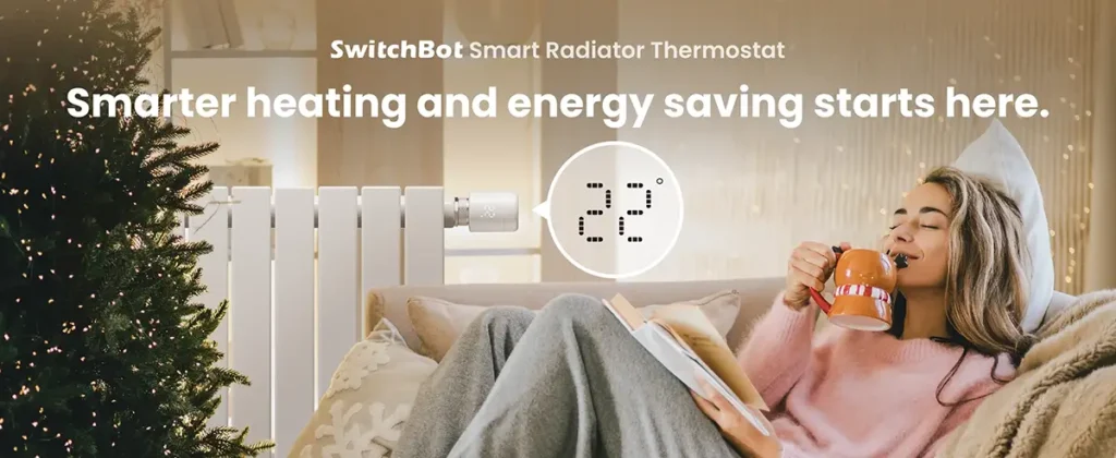 Una mujer disfruta de un ambiente cálido y acogedor en su sofá gracias al Termostato Inteligente para Radiador de SwitchBot. La imagen muestra cómo el dispositivo controla la temperatura del radiador (marcando 22°C) para un mayor confort y ahorro de energía en el hogar durante el invierno.