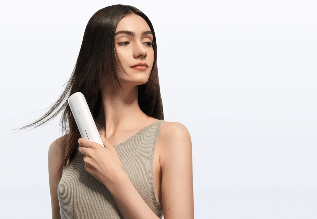 Modelo de pelo largo y oscuro usando el cepillo alisador inalámbrico Xiaomi Cordless Hair Straightener Brush para conseguir un acabado liso, brillante y sin encrespamiento. La imagen muestra la facilidad de uso y el resultado profesional del gadget de belleza.