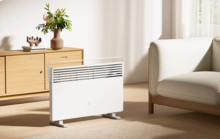 Calefactor convector Xiaomi Mijia Electric Heater 2 con control de temperatura en un salón. El calentador eléctrico blanco de 2200 W muestra su diseño minimalista y el práctico tendedero plegable para secar ropa.
