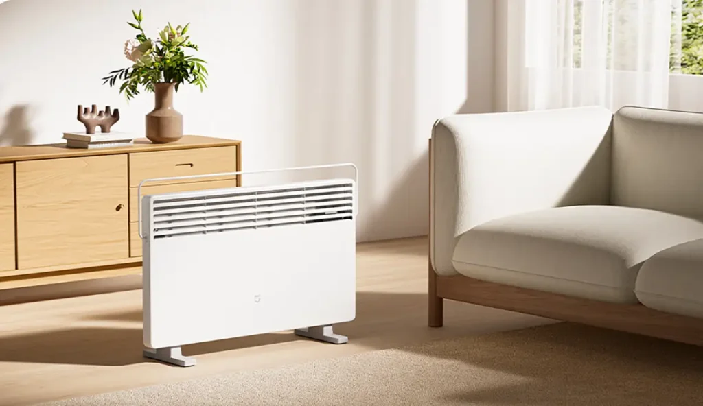Calefactor convector Xiaomi Mijia Electric Heater 2 de color blanco y diseño minimalista, ubicado en un salón moderno. Se muestra con su tendedero superior plegable, ideal para calentar la estancia y secar la ropa.