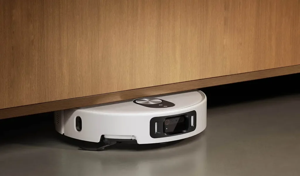 El robot aspirador Xiaomi Robot Vacuum 5 Pro con su radar retráctil dToF limpiando sin esfuerzo debajo de un mueble bajo, demostrando su capacidad para acceder a espacios de hasta 9,5 cm.