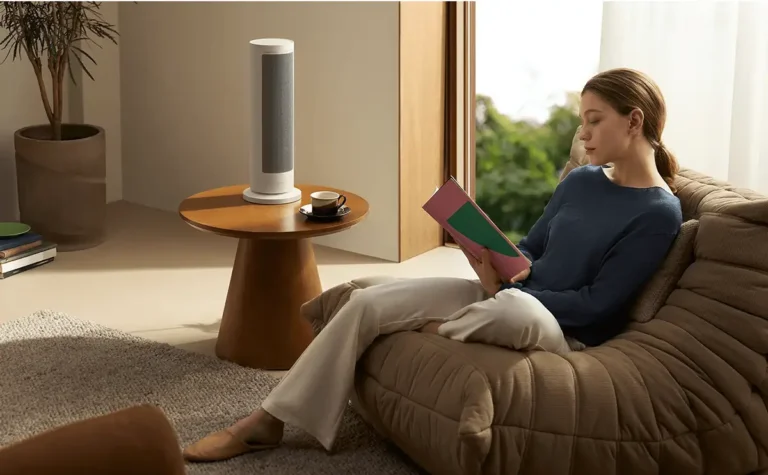 Una mujer disfruta de un ambiente cálido leyendo en el sofá junto al calefactor inteligente Xiaomi Smart Graphene Heater, creando un hogar confortable y moderno