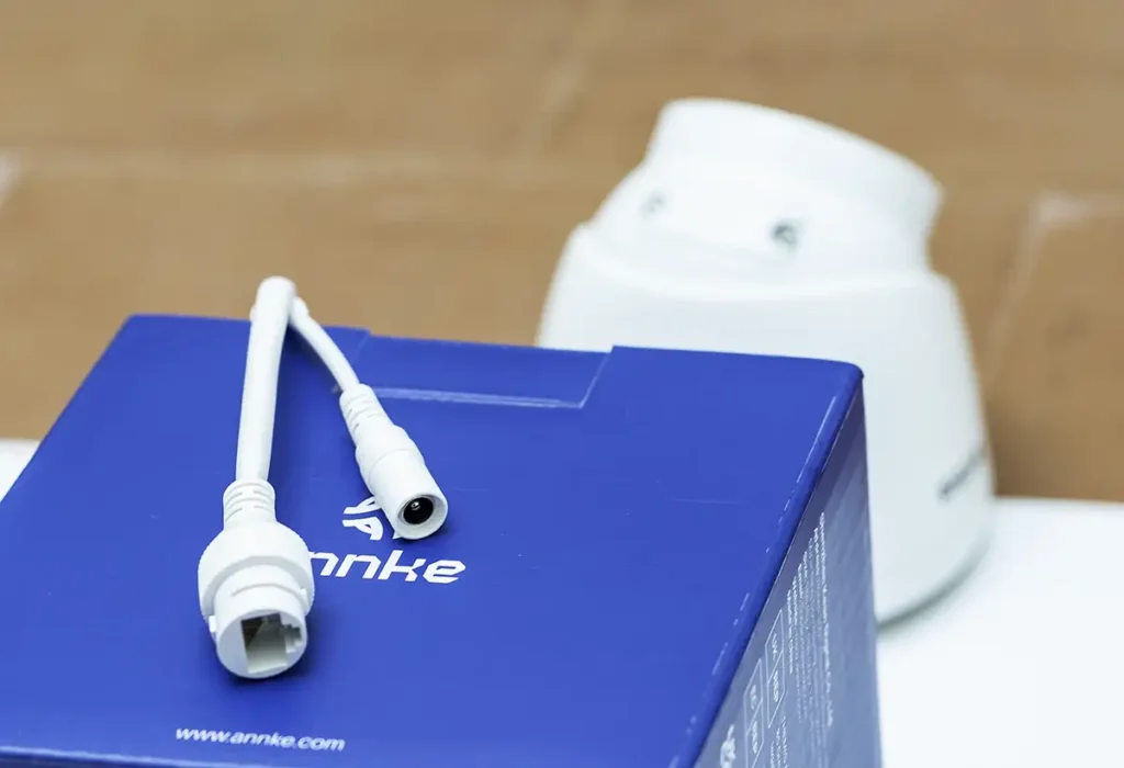 Primer plano de los conectores de la cámara de seguridad ANNKE C500 (I51DM01), mostrando la doble opción de alimentación: el puerto Ethernet RJ45 para PoE y el conector de barril para una fuente de 12V DC.