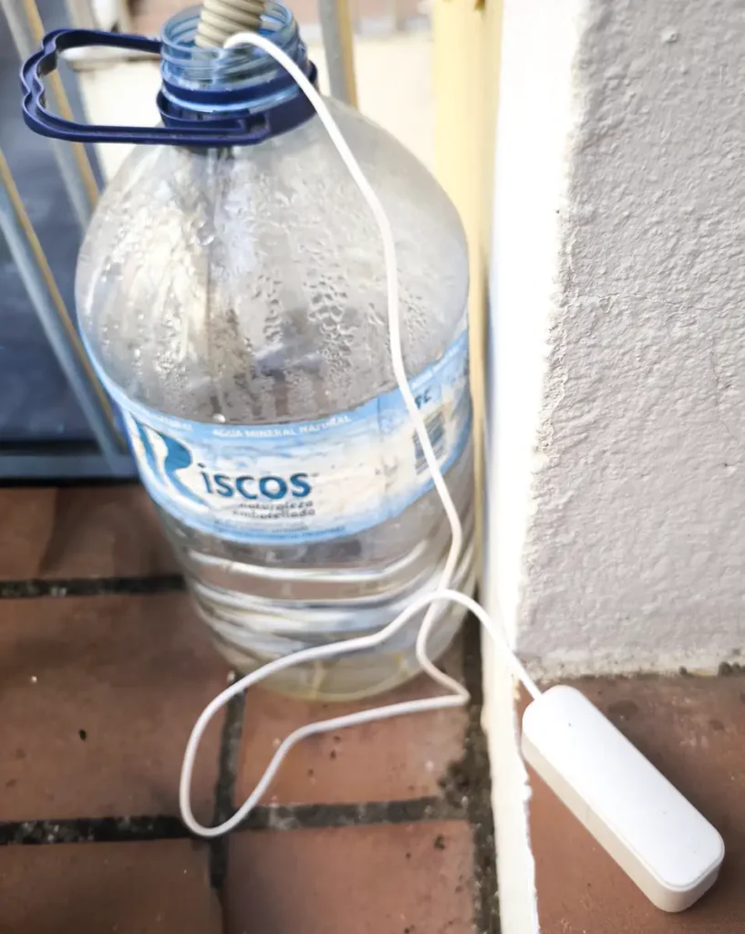 Instalación real de un sensor de nivel de agua Tuya para un proyecto de domótica casero. La sonda del detector se introduce en una garrafa para controlar el agua de condensación del aire acondicionado y evitar desbordamientos.