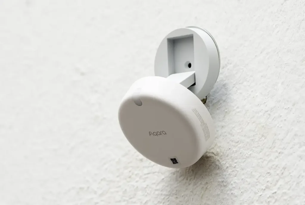 Instalación del sensor de presencia Aqara FP2 en una pared. La base magnética permite orientar el sensor de radar para una detección de presencia precisa en sistemas de domótica como Home Assistant.