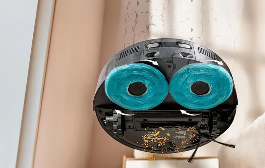 Ilustración técnica del sistema de limpieza del robot aspirador Conga X70. La imagen muestra en detalle su sistema de fregado con doble mopa rotatoria (tecnología Spin) en acción. Se aprecia cómo las mopas azules giran para fregar el suelo mientras el cepillo central y el lateral se encargan de la aspiración de suciedad, ilustrando la capacidad del robot aspirador y friegasuelos para realizar una limpieza completa en una sola pasada