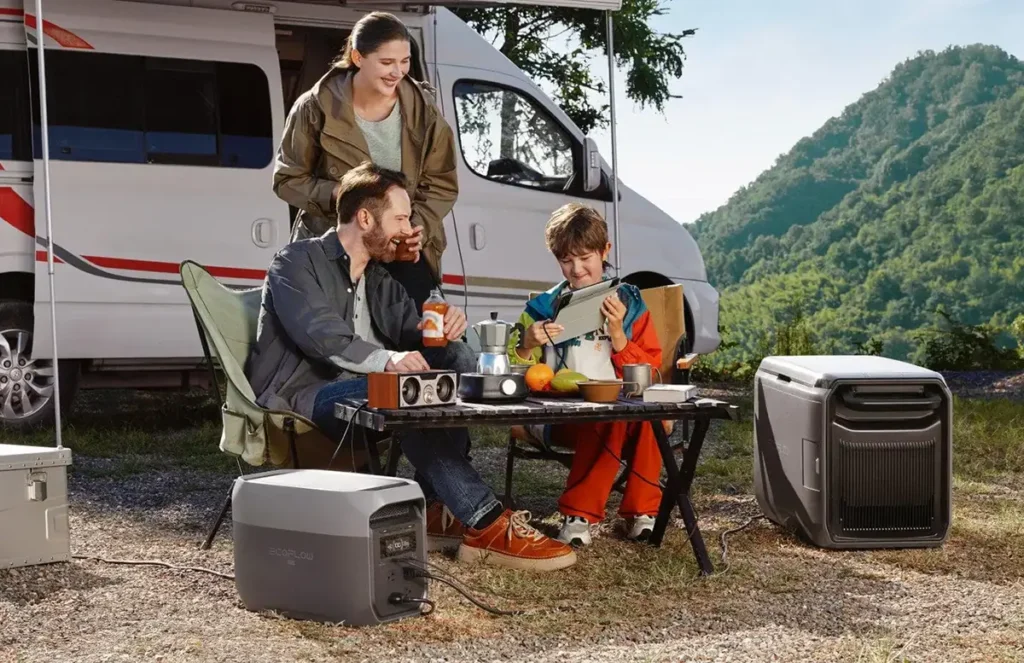Familia disfrutando de un camping con su autocaravana, utilizando una estación de energía portátil EcoFlow DELTA 3 Max para alimentar una cafetera, un altavoz y cargar una tablet, demostrando cómo tener energía off-grid para viajes y ocio al aire libre.