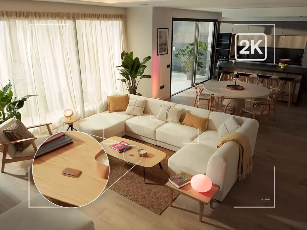 Vista desde una cámara Philips Hue Secure 2K mostrando un salón moderno con gran detalle. Un zoom resalta una cartera sobre la mesa, demostrando la nitidez de la resolución 2K para la vigilancia interior y la seguridad del hogar.