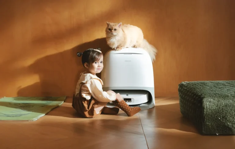 Imagen promocional del Roborock Qrevo Curv 2 Pro que ilustra su convivencia segura en un hogar. Una niña pequeña está sentada en el suelo junto al robot y su base, mientras un gato de pelo largo descansa tranquilamente sobre la estación de autolimpieza.