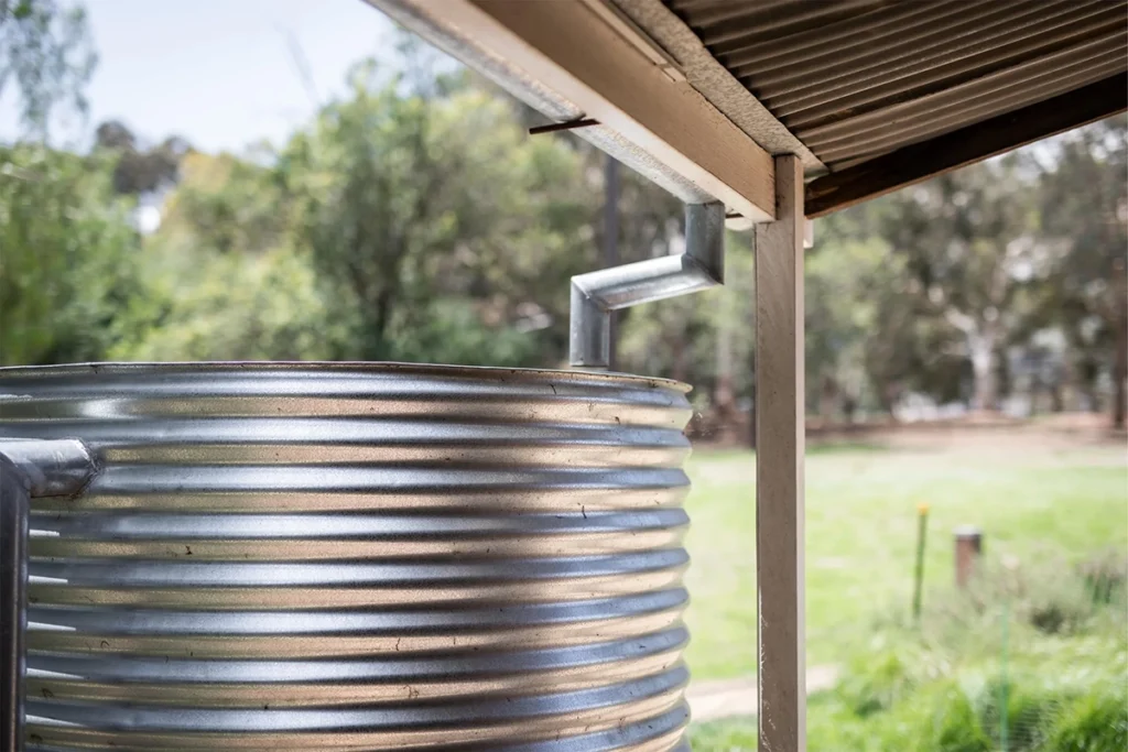Tanque de agua metálico en un jardín, mostrando un escenario ideal para la instalación del Shelly BLU Distance en la tapa para un control inteligente y sin cables del nivel de líquido almacenado.