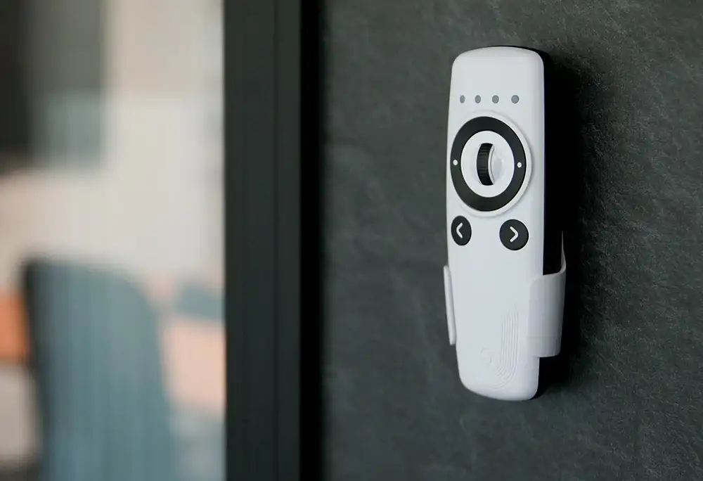 Mando a distancia Shelly BLU Remote Control ZB en color blanco, instalado en su soporte de pared sobre una superficie oscura. Accesorio ideal para la domótica del hogar y tener el control siempre localizado.