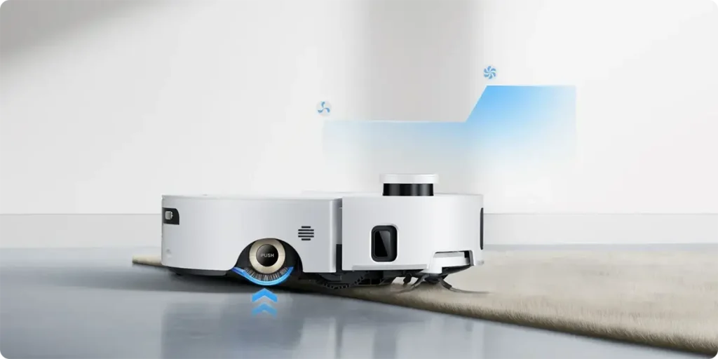 El robot aspirador Dreame Aqua10 Ultra Roller limpia sin problemas hogares con suelos mixtos. Su chasis se eleva para subir alfombras altas sin atascarse y aumenta automáticamente la potencia de succión para eliminar la suciedad incrustada.