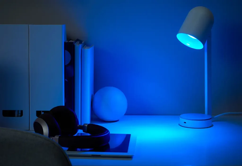 Lámpara de escritorio de IKEA con una bombilla inteligente KAJPLATS GU10 compatible con Matter, iluminando una zona de trabajo con una intensa luz azul para mostrar las capacidades de color del nuevo sistema.