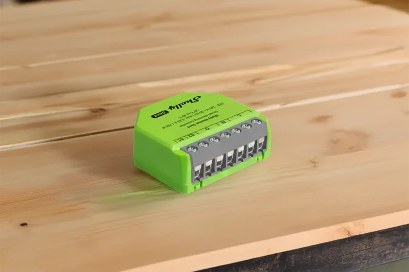 Shelly Dimmer Gen4 de color verde instalado sobre una mesa de madera, mostrando los bornes de conexión frontales