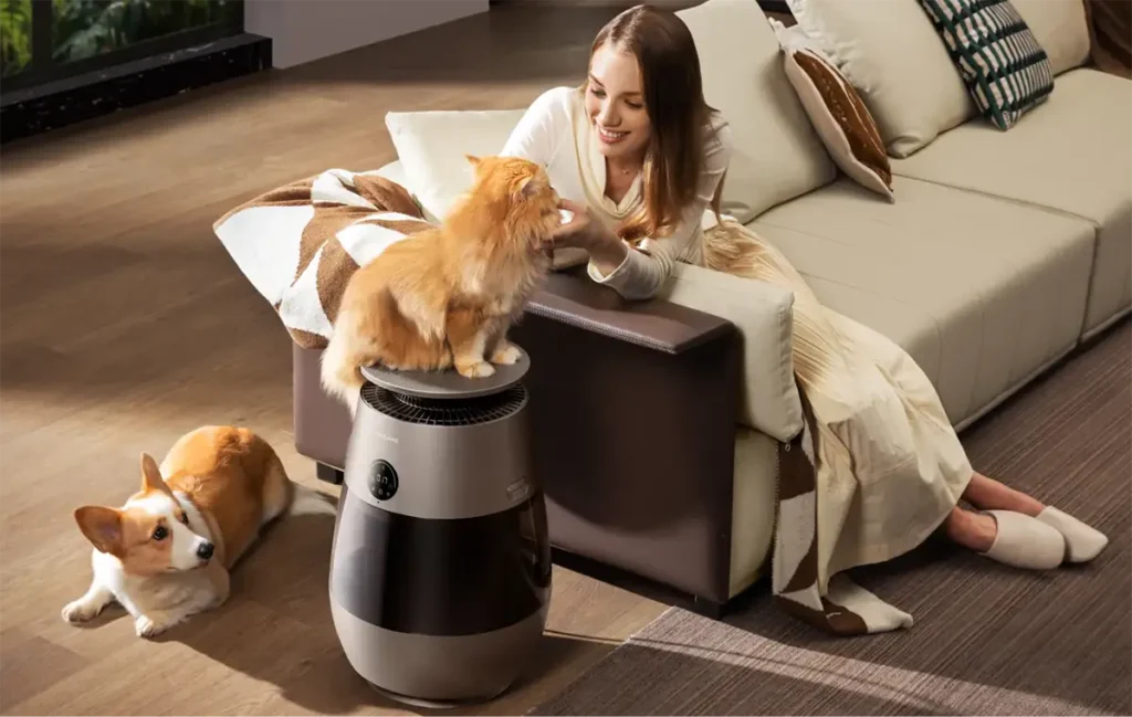 Purificador de aire para mascotas Dreame AP10 en un salón, mostrando cómo se integra en un hogar con animales mientras una mujer interactúa con su gato y su perro.