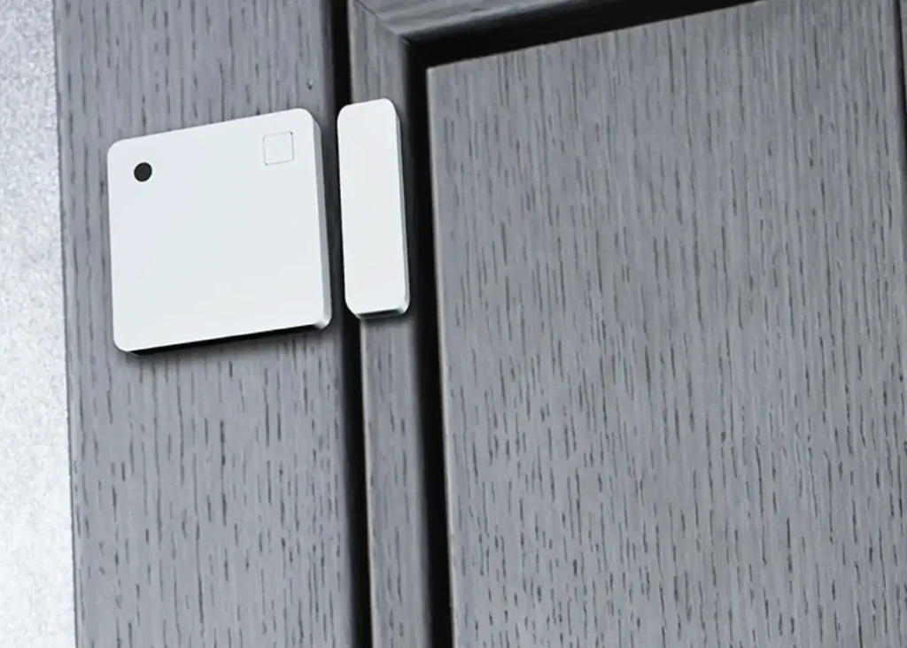 Sensor Shelly Wave Door/Window LR instalado en una puerta de madera gris