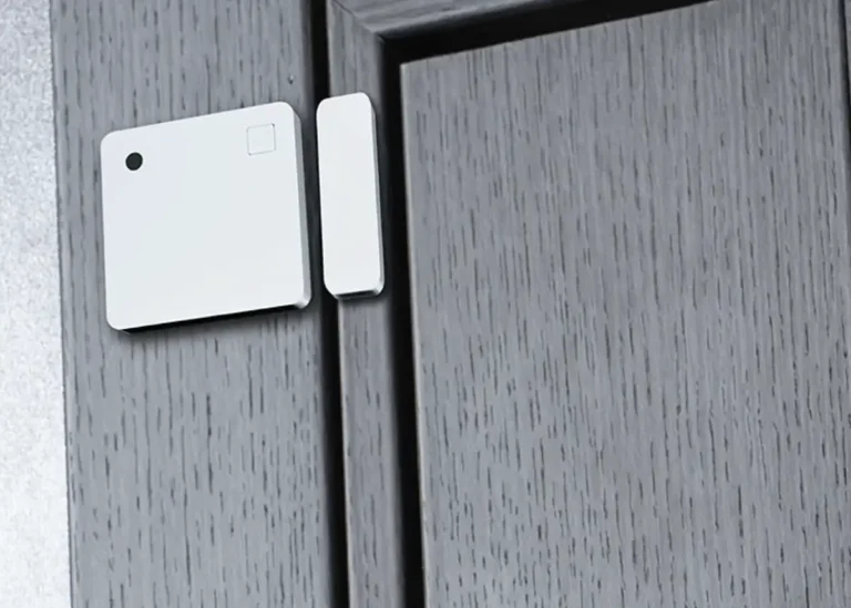 Sensor Shelly Wave Door/Window LR instalado en una puerta de madera gris