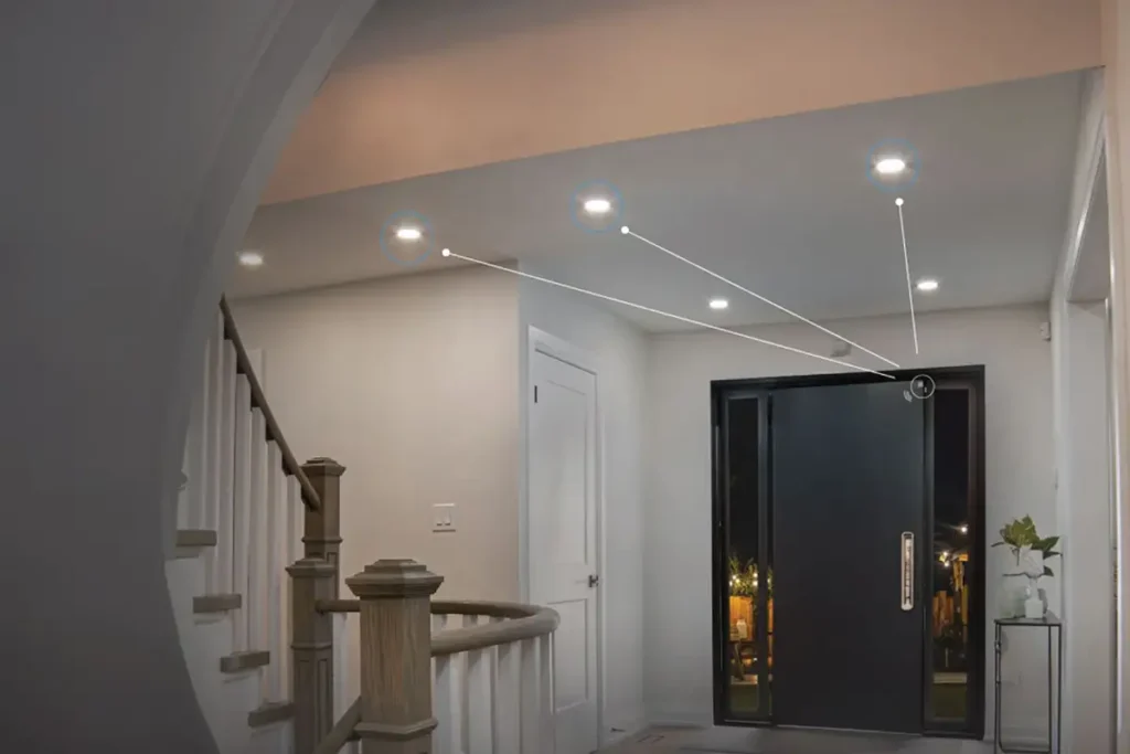 Entrada de una vivienda con puerta principal abierta donde un sensor Shelly Wave Door/Window LR en el marco enciende automáticamente los focos del pasillo.