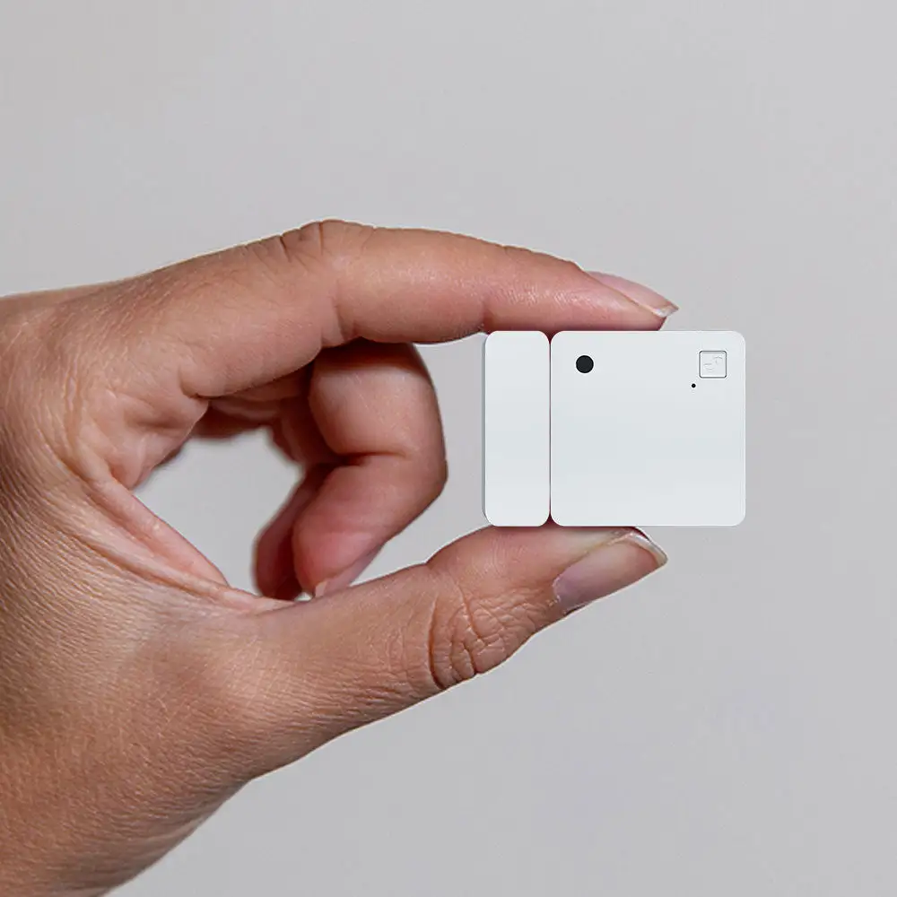 Sensor Shelly Wave Door/Window LR sujetado entre los dedos de una mano, mostrando su tamaño compacto para puertas y ventanas.