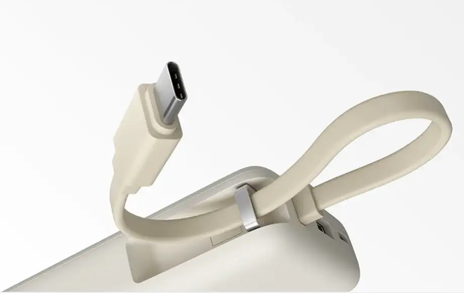 Detalle del cable USB-C integrado de la Xiaomi 67W Power Bank (Integrated Cable), con el cordón sujeto al cuerpo de la batería externa en color beige