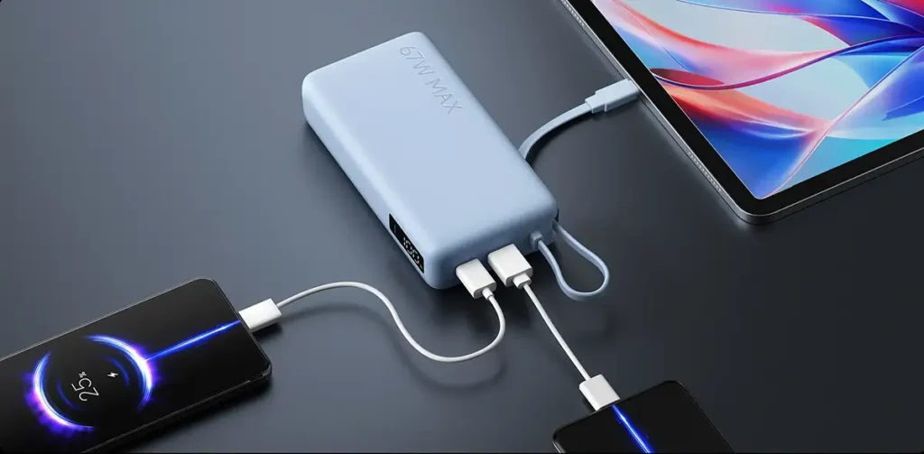 Xiaomi 67W Power Bank en color azul cargando varios dispositivos a la vez mediante el cable USB-C integrado y los puertos USB-C/USB-A, sobre una mesa junto a un móvil y una tablet.