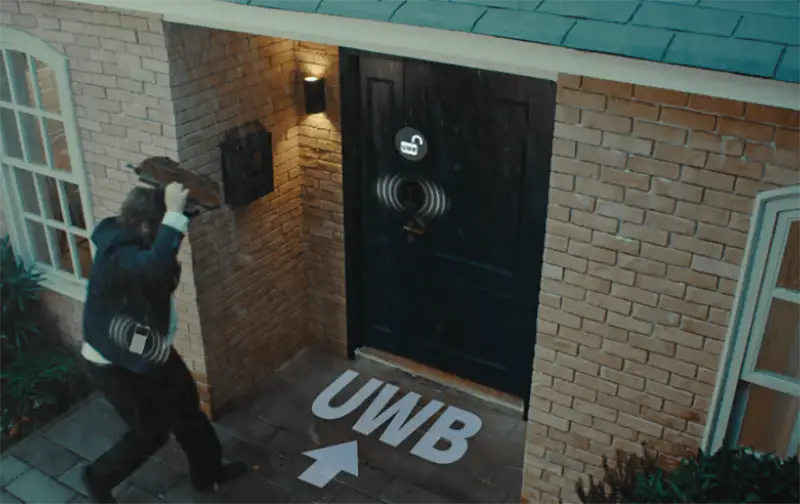 Persona acercándose a una puerta de casa mientras se destaca la tecnología UWB (ultra-wideband) para el desbloqueo manos libres de una cerradura inteligente.