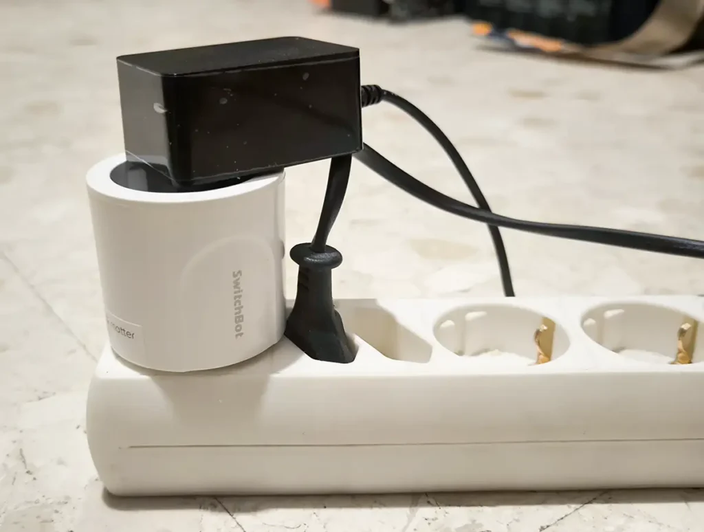 SwitchBot Plug Mini EU en una regleta sin tapar tomas laterales, ejemplo de uso con un cargador grande