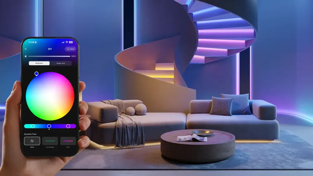 Mano sujetando un smartphone con la app Dreamehome y una rueda de color, frente a un salón iluminado con luces LED multicolor y una escalera de caracol.