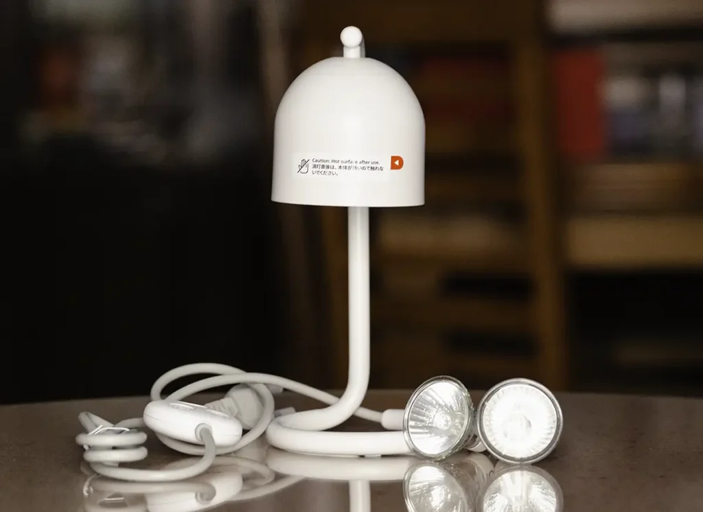 Contenido de la caja del SwitchBot Candle Warmer Lamp con la lámpara blanca, el controlador en el cable y dos bombillas GU10 de 50W