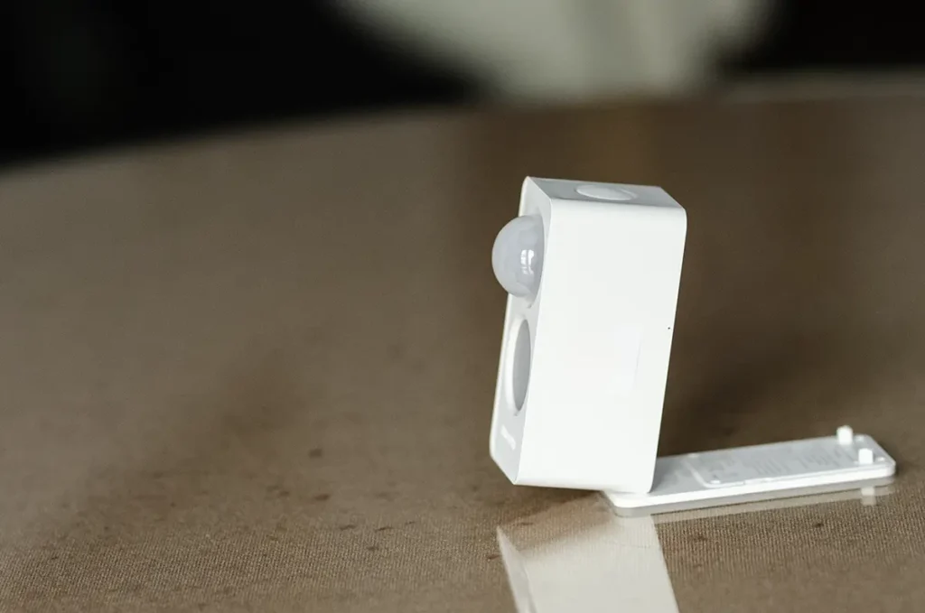 Sensor de presencia Meross MS605 visto de perfil con soporte de montaje y botón superior de emparejamiento