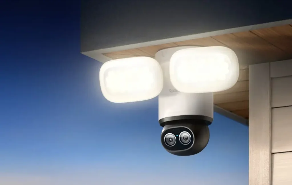 Cámara exterior Reolink TrackFlex Floodlight WiFi con doble lente 4K y focos integrados instalada bajo un tejado