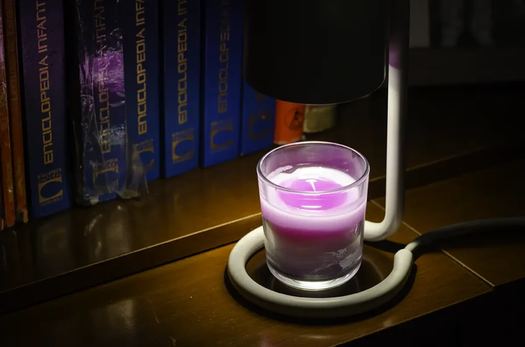SwitchBot Candle Warmer Lamp calentando una vela aromática morada, con detalle de la cera derretida de forma uniforme bajo la lámpara