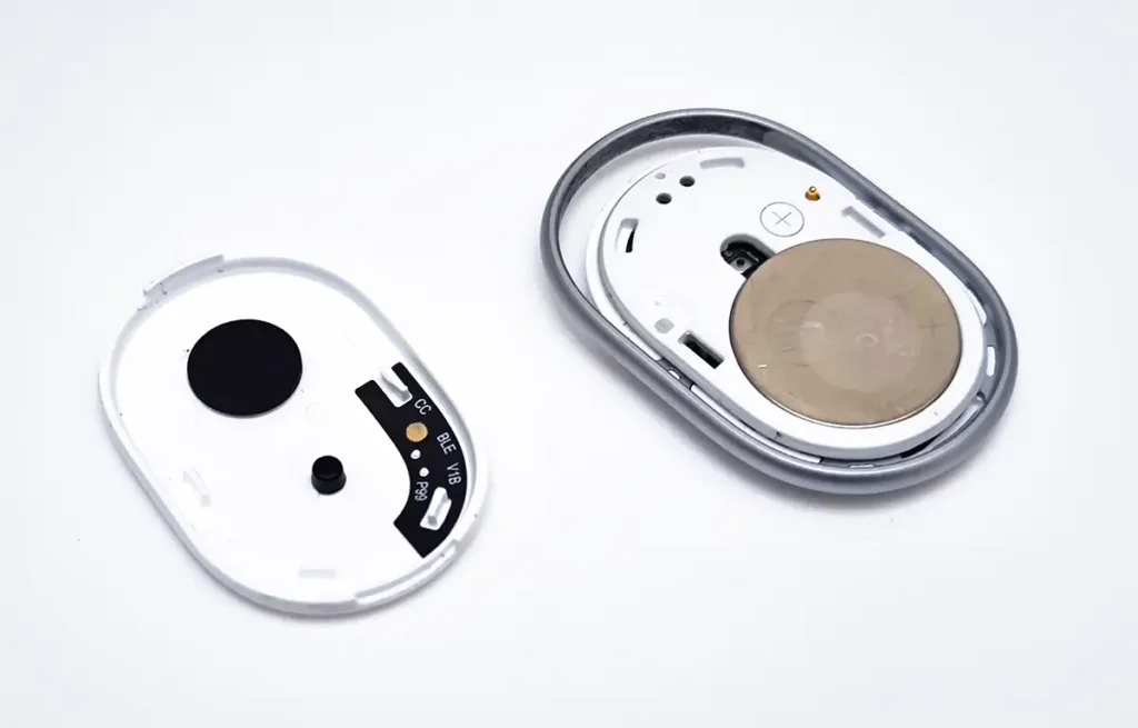 Xiaomi Tag abierto para acceder a la batería CR2032, con la tapa retirada y el interior del rastreador sobre fondo blanco.