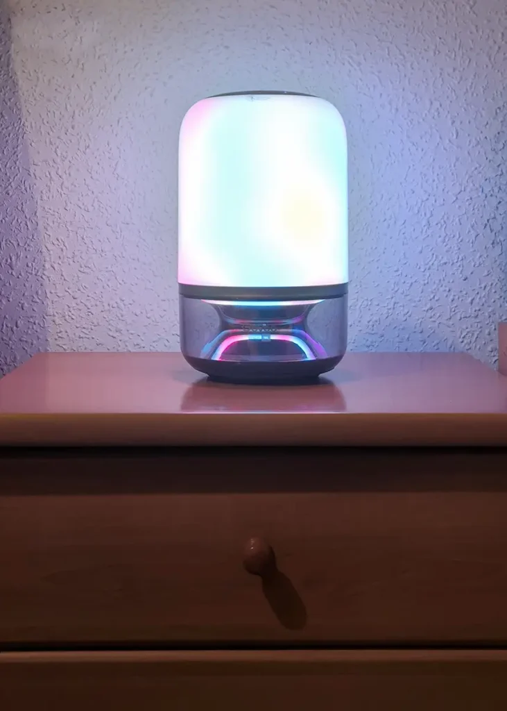 Govee Table Lamp 2 Pro x Sound by JBL encendida sobre una mesita de noche con iluminación multicolor en la parte superior e inferior