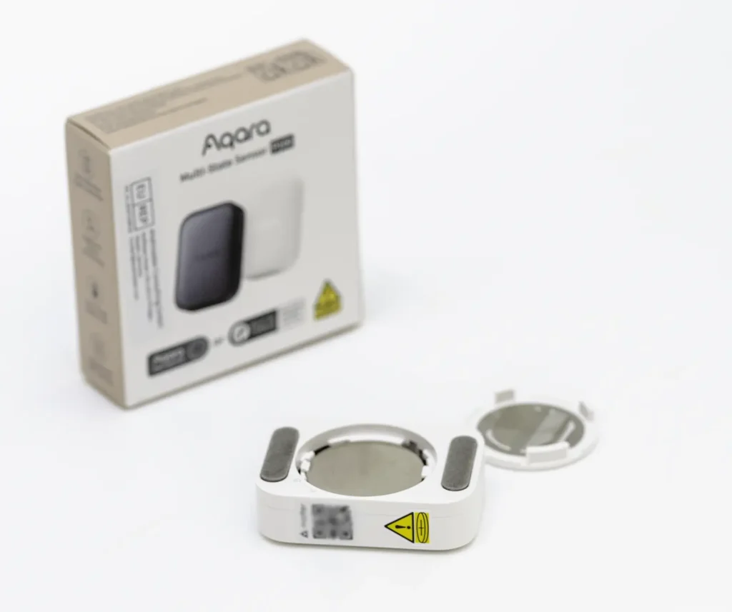 Parte trasera del Aqara Multi-State Sensor P100 con compartimento de batería CR2450 y adhesivos de montaje