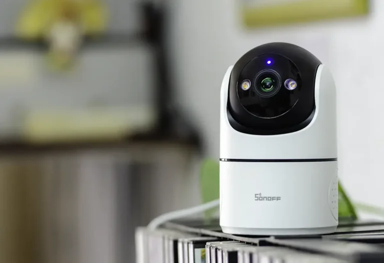 SONOFF CAM Pan-Tilt 2 encendida sobre un mueble con la lente, LED de estado y luces frontales visibles