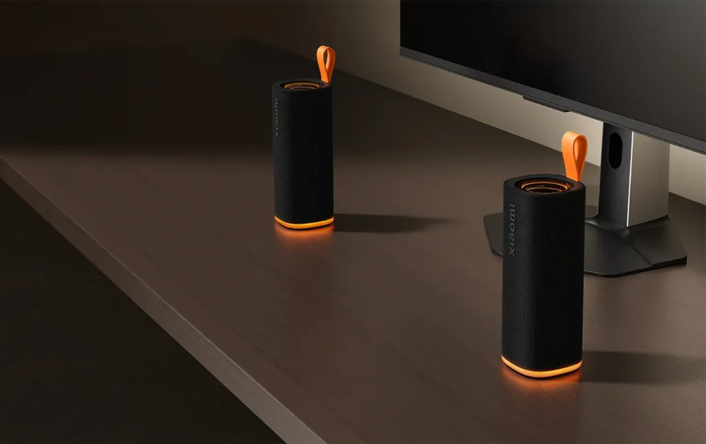 Dos Xiaomi Sound Play en color negro con iluminación naranja junto a un monitor