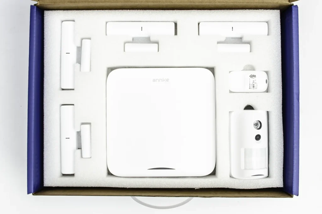 Kit de alarma ANNKE en su caja con panel de control, sensores de apertura y detector PIR con cámara.