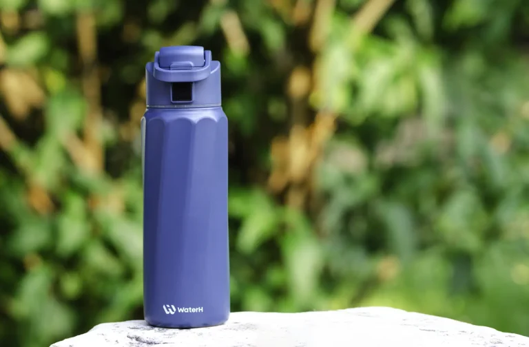 Botella inteligente WaterH Boost color azul sobre superficie de piedra con fondo natural