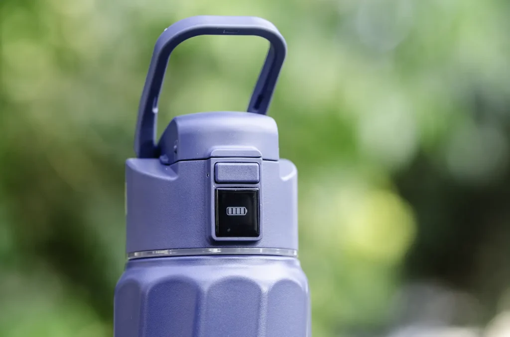 Detalle de la tapa de la botella WaterH Boost con el asa, el botón de apertura y la pantalla mostrando el nivel de batería
