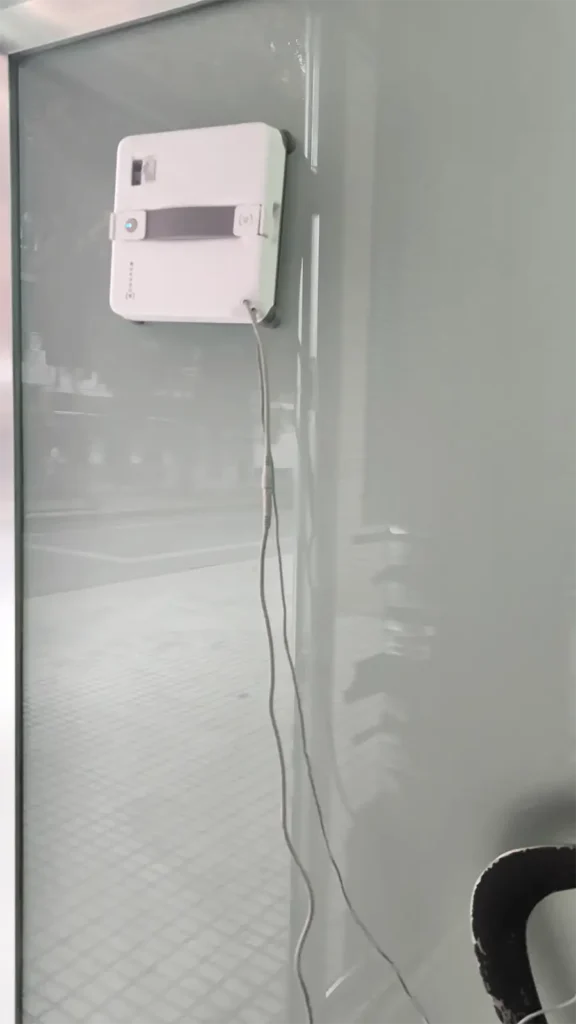 ECOVACS WINBOT Mini 2 limpiando la puerta de cristal de un local en desuso
